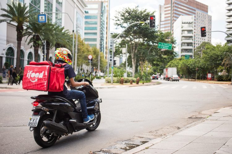TQ SÃO PAULO 17.03.2020 METRÓPOLE EXCLUSIVO EMBARGADO ENTREGA COMIDA VIA APLICATIVOS EM TEMPOS DE CORONAVÍRUS Na foto o motoby Emanuel Araujo, de 22 anos, faz entrega na Vila Olimpia. Motoboys e Bikeboys em compasso de espera sobre aumentar ou diminuir o trabalho de entrega de aplicativos via Ifood, Rappi e Ubereats devido ao desdobramento da pandemia de Coronavírus no país. Alguns entrevistados dizem que movimento aumentou, outros que continua o mesmo ou mesmo diminuiu, de concreto muito poucos portam alcool gel em seus kits de trabalho (celular, bicicleta ou moto), nenhum foi visto de máscara. Empresas limitam-se a passar mensagens alertando-os a lavarem sempre as mãos durante as entregas. FOTO TIAGO QUEIROZ / ESTADÃO