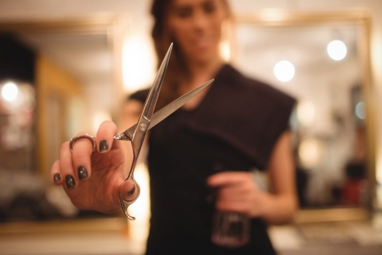 Female hairdresser holding scissor at saloon