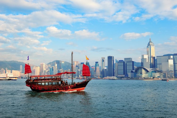 Boat in Victoria Harbor in Hong Kong with city skyline in the day