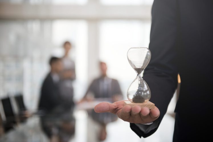 Businessman holding an hour glass, signifies the importance of being on time