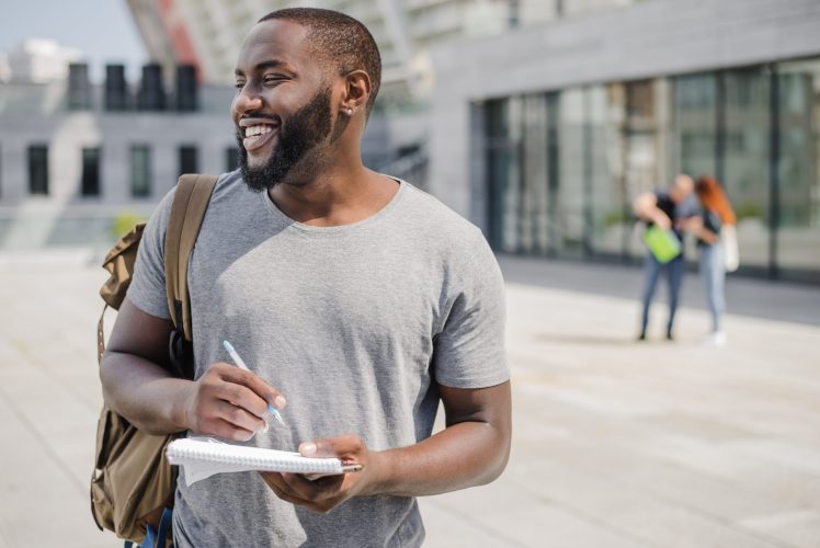 man-holding-notebook-standing-outside