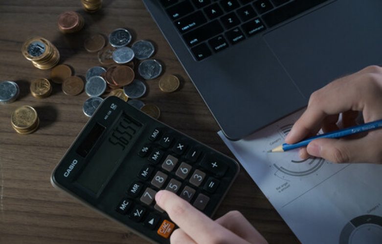 Homem utilizando planilha, calculadora e computador calcula receitas e despesas. *** Local Caption *** Finanças