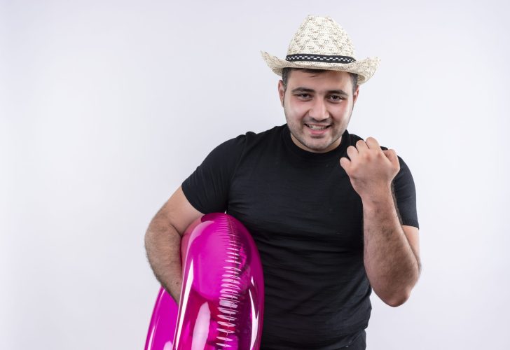 young traveler man in black t-shirt and summer hat holding inflatable ring happy and positivesmiling cheerfully standing over white background